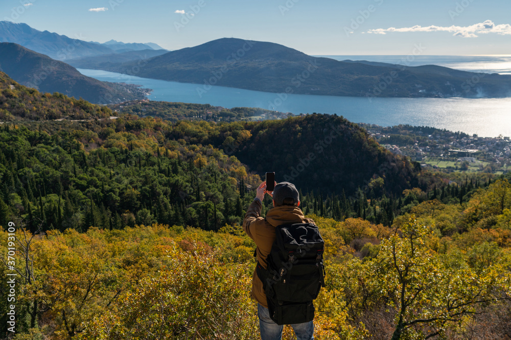 Traveler with a backpack and a smartphone stands on a mountain