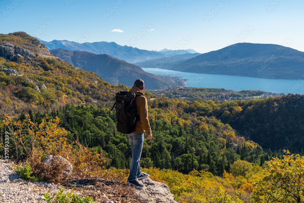 A traveler with a backpack stands on the top of the mountain 