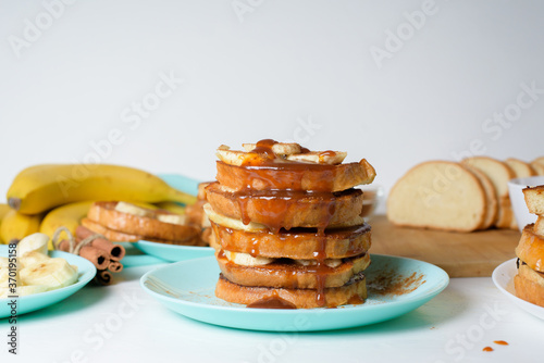 French toast with banana and homemade caramel with cinnamon, Breakfast dessert on a blue plate on a light background