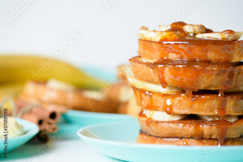 French toast with banana and homemade caramel with cinnamon, Breakfast dessert on a blue plate on a light background