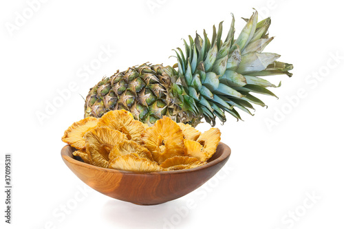 Pineapple and slices of dried pineapple in a wooden bowl isolated on white