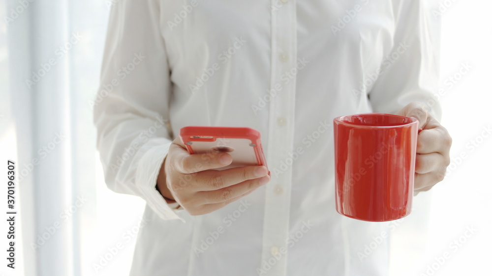 woman standing with a cup of red coffee and a smartphone woman standing with a cup of red coffee and a smartphone