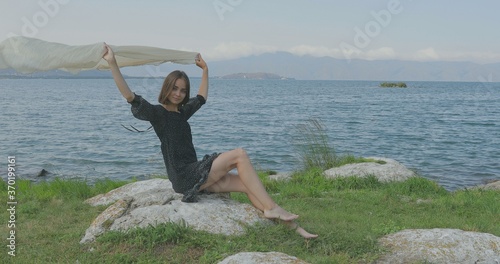 Girl stait on the pier, walking on the beach. Posing in front of the camera, Smiling, walking barefoot in the sand, the wind playing with a shawl
 photo