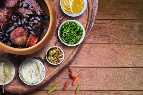 Feijoada. Traditional Brazilian food. Ceramic bowl isolated on rustic wooden background. Top view.