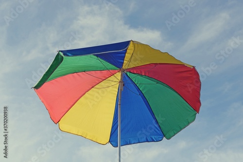 open multicolored parasol with blue sky in the background