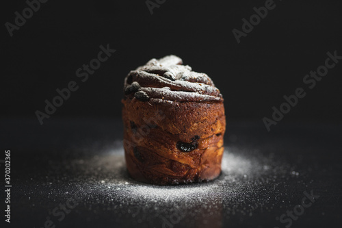 Easter cake kraffin sprinkled with icing sugar on a black background. Holiday baking. Easter traditions. photo