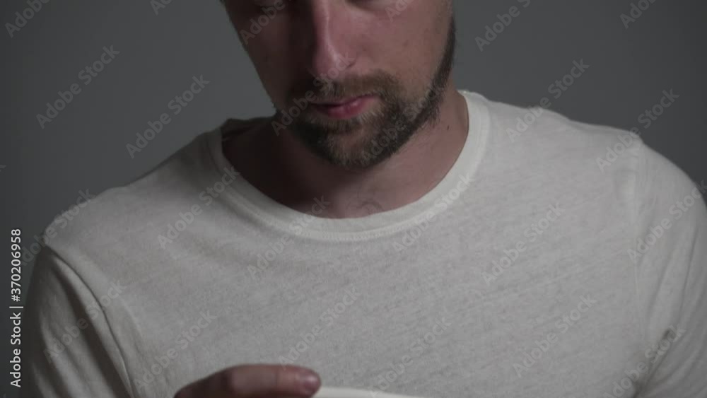 A young Caucasian man is sick and have his body temperature measured with an electronic thermometer. High temperature concept. Man feels badly ill. Infection, coronavirus virus and covid 19