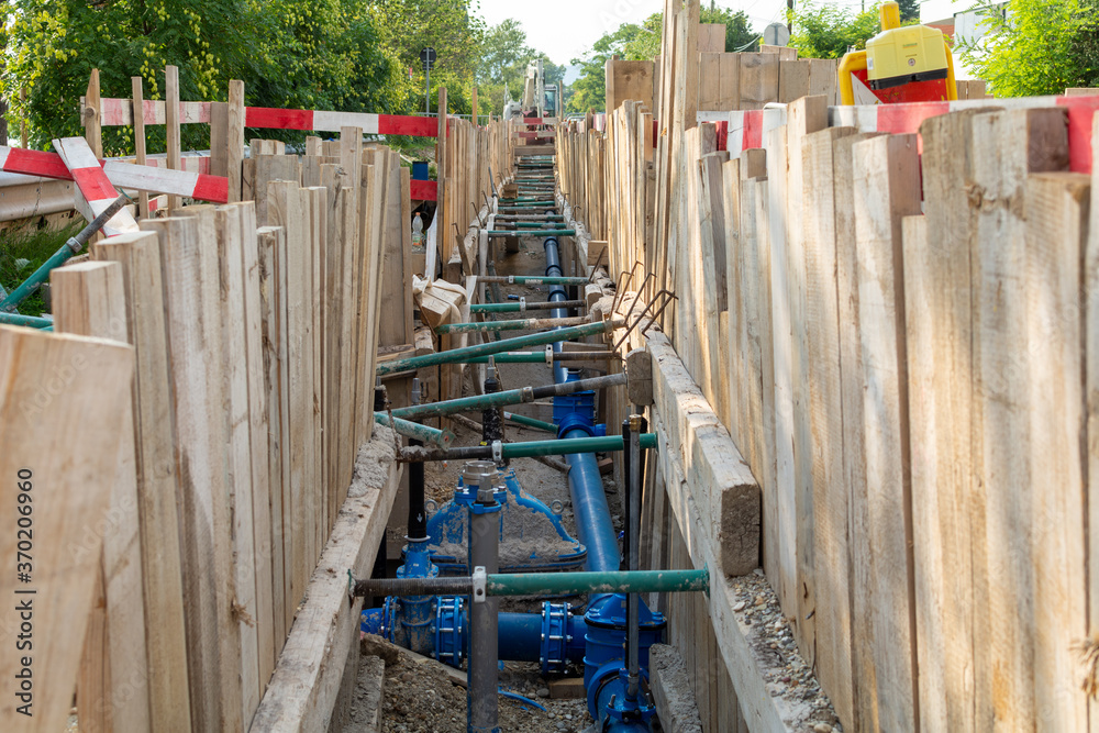 Repair of roads and underground utilities. Big trench on the road with a pipe, the process of repair, or replacing water pipes in a city.