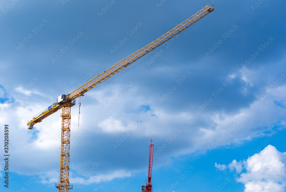 two tower cranes in front of a cloudy sky