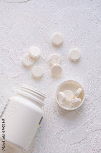 White pills and pills cantainer on a white background top view.