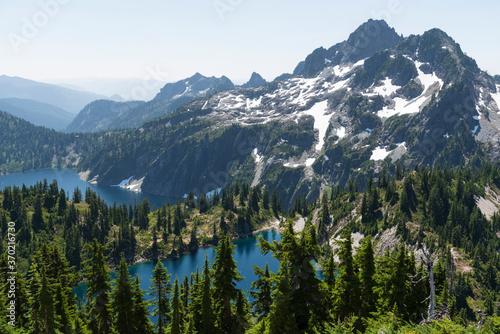 High angle view of gorgeous alpine mountain peaks surrounding lakes in evergreen valley.