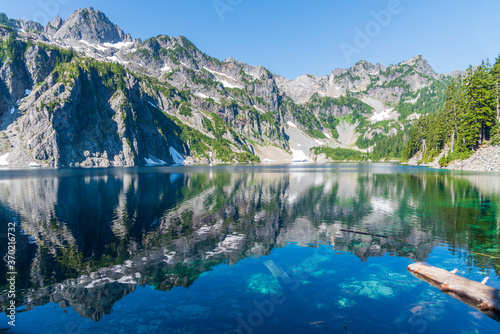 Alpine mountains reflecting into pristine placid lake in morning light. 