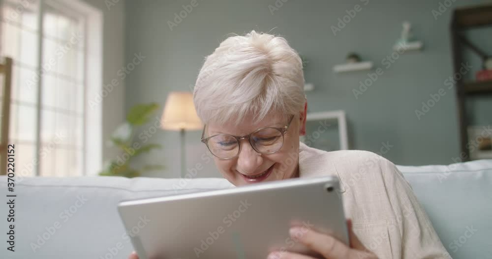 Caucasian woman in 50s having a video meeting at home. Senior lady looking at screen of tablet and talking with employees during lockdown 4k footage Caucasian woman in 50s having a video meeting at home. Senior lady looking at screen of tablet and talking with employees during lockdown 4k footage
