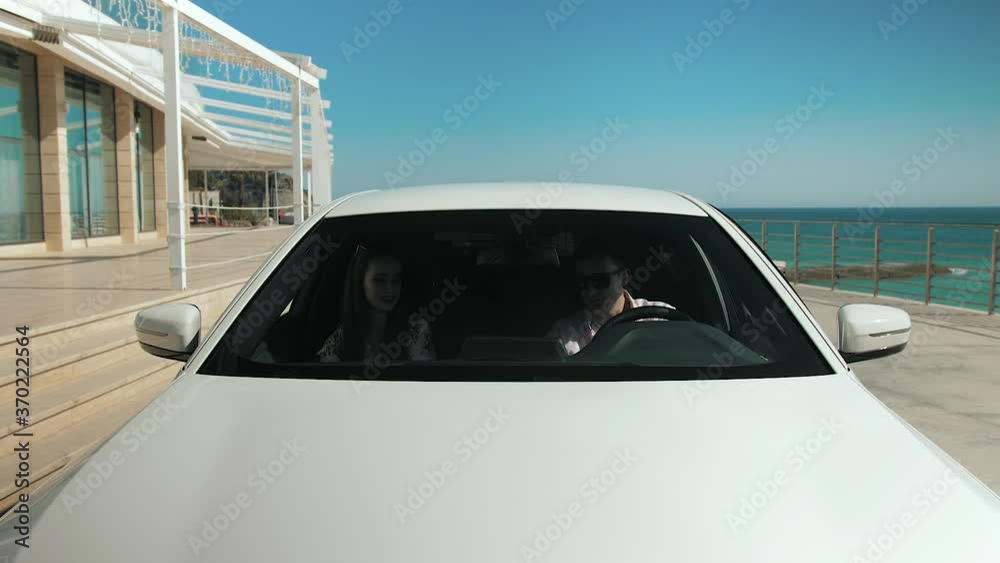 young couple in a car by the sea, getting out of the car
