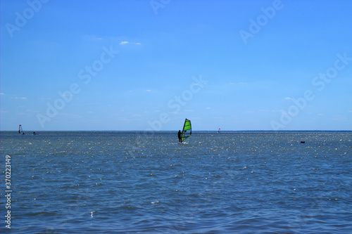 
A straggler in a windsurfer regatta picks up speed against a background of blue sea and sky
