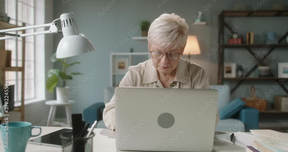 Joyful caucasian lady finishing a project. Happy mature woman closing her laptop, ending her working day at home during self isolation 4k footage