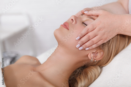 Close up of a beautiful woman relaxing at spa center  getting face massage