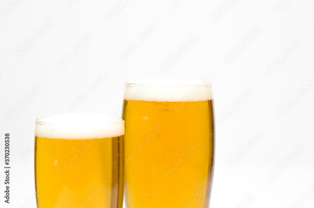 Two glasses full of beer with foam along on a white background. Two glasses full of beer with foam along on a white background.