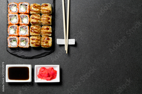 Sushi. Sushi rolls on a stone stick with chopsticks and sauce in a saucer. Sushi food photo for menu. Sushi baked with tuna and cucumber