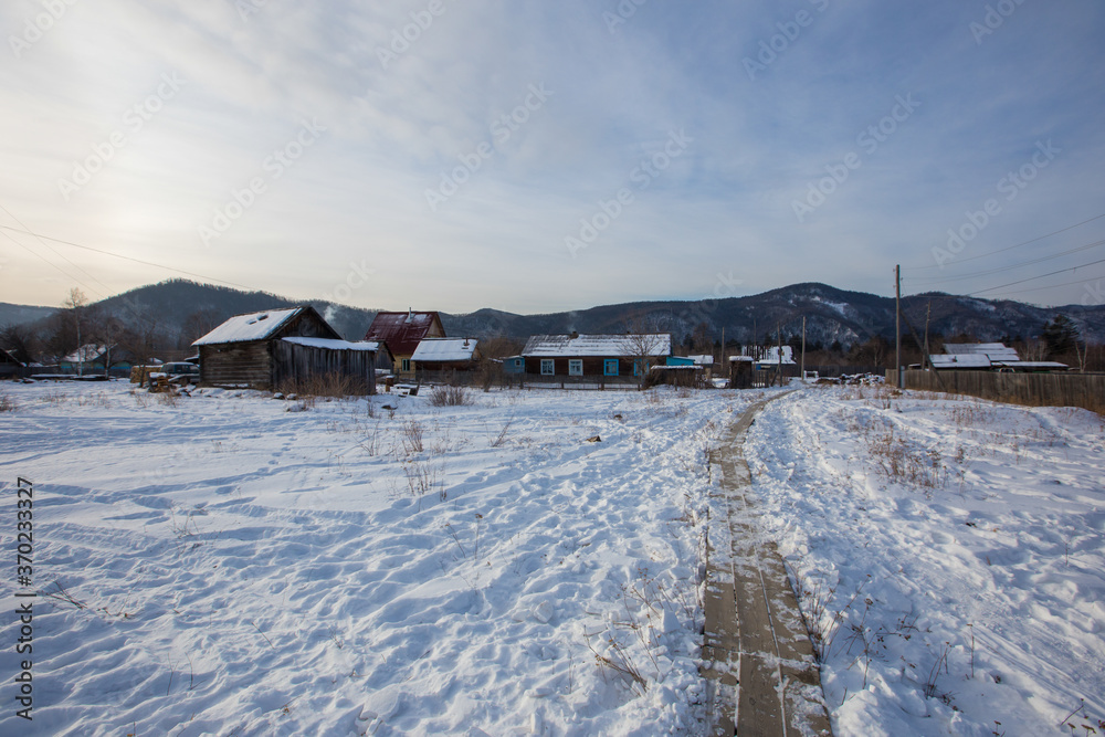 Russian village. Wooden huts with smoke from chimneys in the winter season Russian village. Wooden huts with smoke from chimneys in the winter season