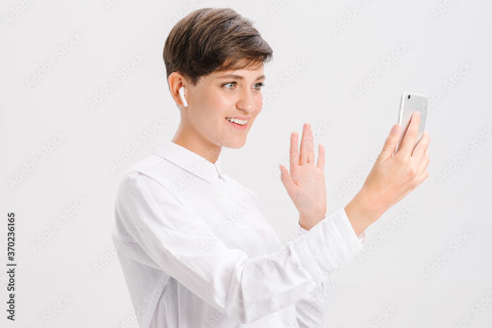 smiling woman uses wireless headphones for a video call and showing like. white background in studio. online business meeting concept. smiling woman uses wireless headphones for a video call and showing like. white background in studio. online business meeting concept.