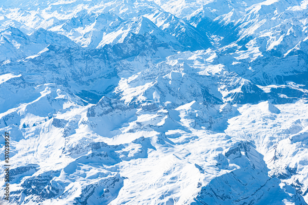 Blue planet earth unique alpine aerial panorama. High altitude aerial view of snow capped central European Alps, seen from an airplane cabin window. Enviromental conservation concept. Blue planet earth unique alpine aerial panorama. High altitude aerial view of snow capped central European Alps, seen from an airplane cabin window. Enviromental conservation concept.