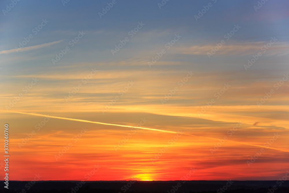 Sunset with blue sky and bright trace of an airplane