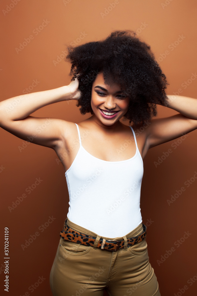 pretty young african american woman with curly hair posing cheerful gesturing on brown background, lifestyle people concept pretty young african american woman with curly hair posing cheerful gesturing on brown background, lifestyle people concept
