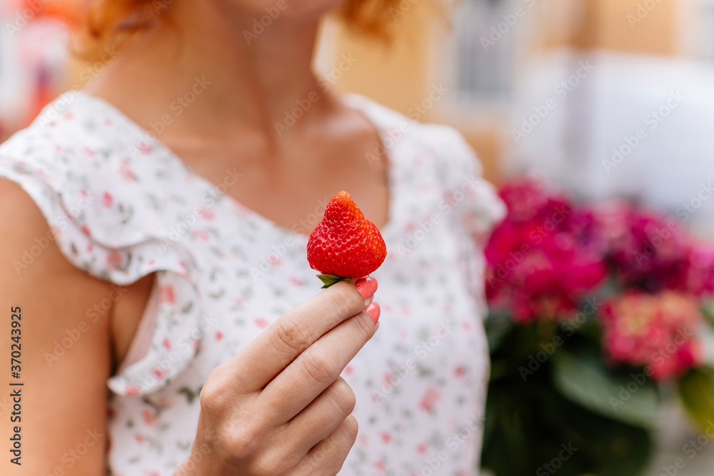 A girl is holding strawberry with a blur background A girl is holding strawberry with a blur background