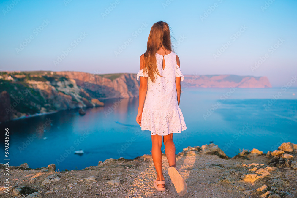 Little girl on top of a mountain enjoying valley view before sunset
