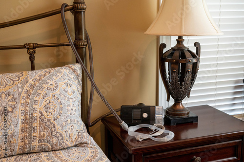 CPAP machine sitting on night stand with nose pillow mask