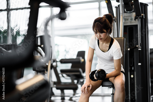 beautiful asian woman lifting dumbbells cheerful in sports fitness gym , excersie and healthcare concept