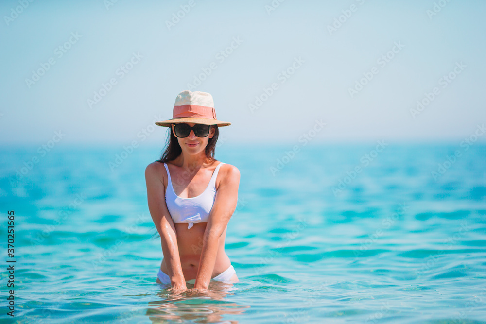 Young beautiful woman having fun on tropical seashore. Happy girl background the blue sky and turquoise water in the sea Young beautiful woman having fun on tropical seashore. Happy girl background the blue sky and turquoise water in the sea