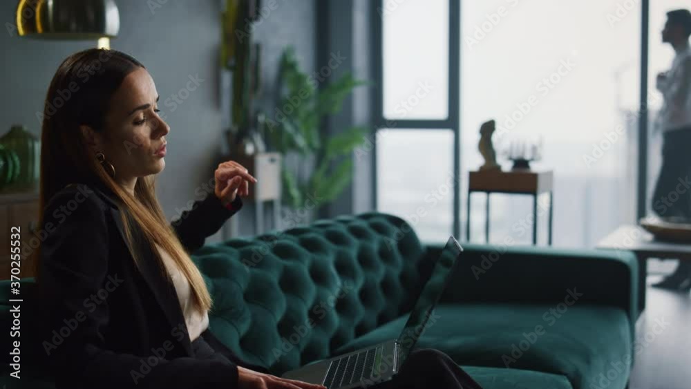 Businesswoman chatting on laptop at workplace. Businessman walking in office Businesswoman chatting on laptop at workplace. Businessman walking in office