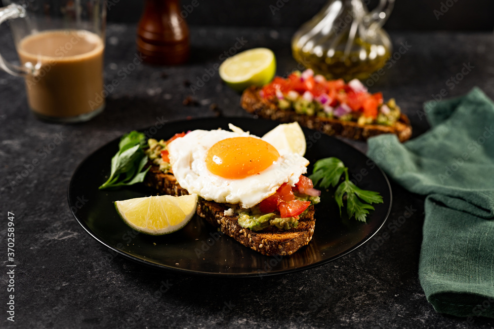 Close up of avocado toast with fried egg and tomatoes Close up of avocado toast with fried egg and tomatoes