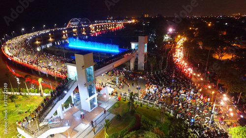 Aerial view of nighttime fountain attraction at Surabaya bridge, East Java, Indonesia which attracts local tourists

