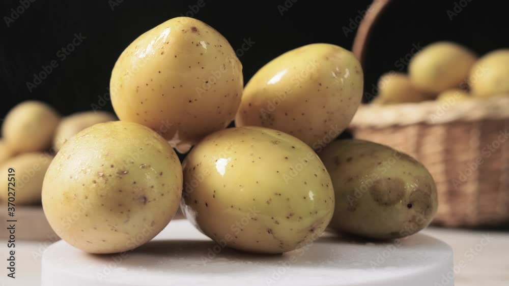 Raw potato on table against dark background Raw potato on table against dark background