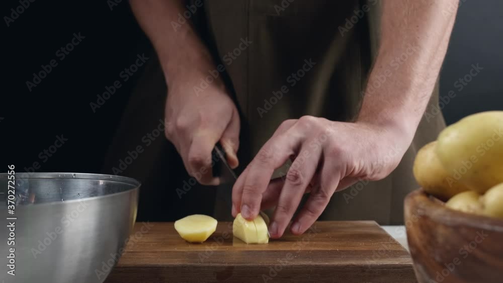Man cutting raw potato at table, closeup Man cutting raw potato at table, closeup