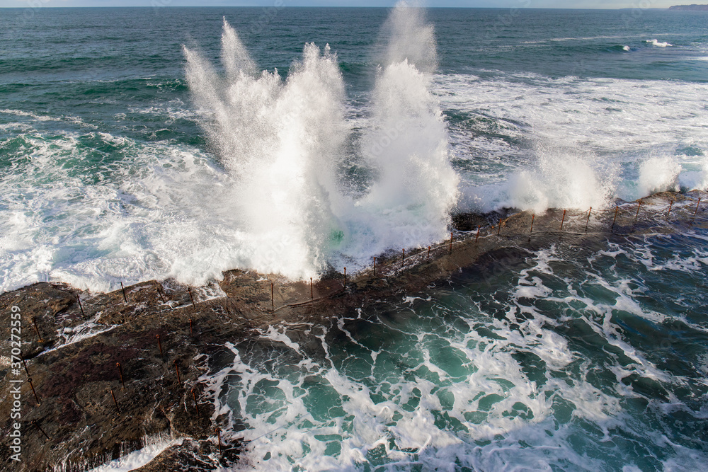 Fototapeta premium Wave crashing into the rocky coastline.