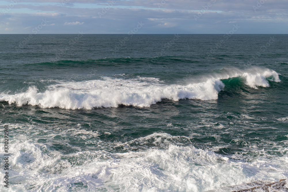 Ocean waves with cloudy sky.