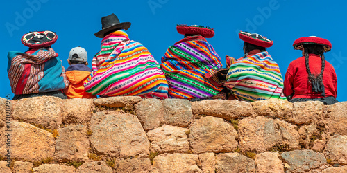 Peruvian Quechua indigenous people in traditional clothing on an Inca wall in Chinchero, Cusco, Peru. photo