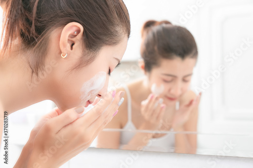 Young beauty woman washing her face in bathroom.