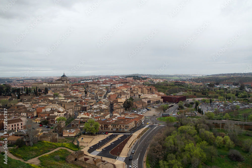 Cityscape. Architecture. Aerial view of the ancient city of Toledo, Spain. The historical buildings, streets, highway and countryside fields. 