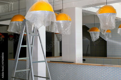 Ongoing renovation and interior remodeling works in a soon to be open new cafe outlet as new ceiling lamp lights are being fitted.