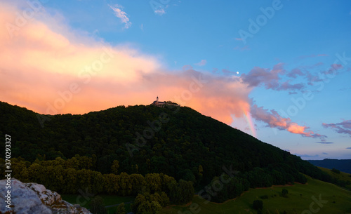 Burck Teck near Kirchheim on a green hill with trees, blue sky with orange clouds, stone in the foreground. Swabian Alb, Germany. photo