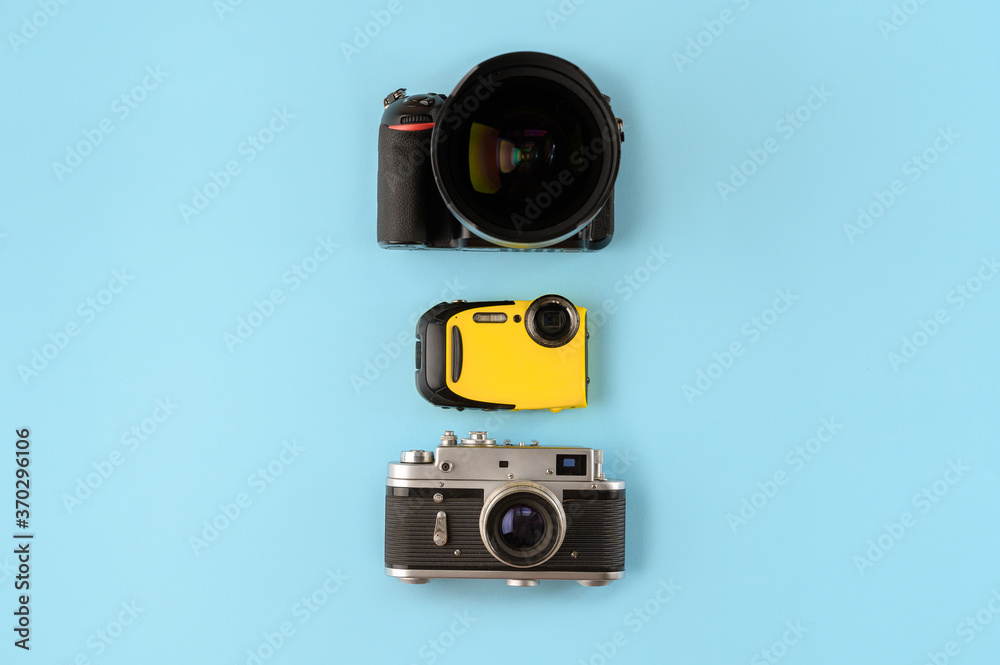 Fototapeta premium Camera evolution.Cameras of different types and generations on a blue background, top view,flat lay.