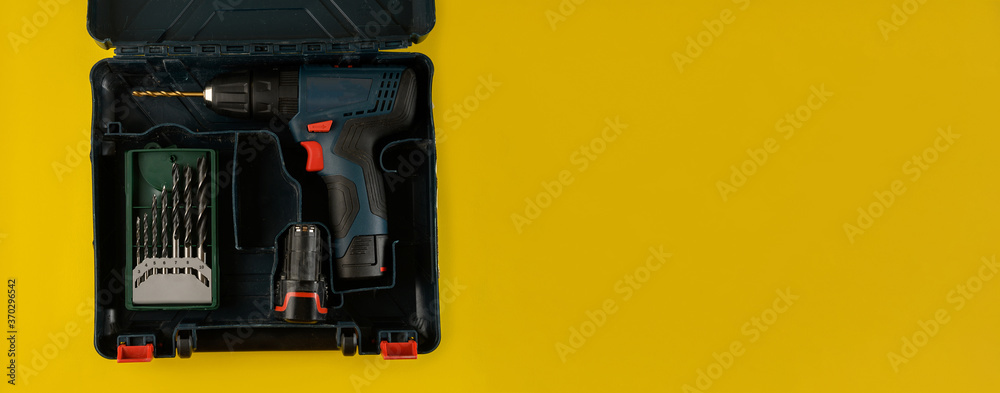 cordless drill, screwdriver with drill bit on yellow background,top view