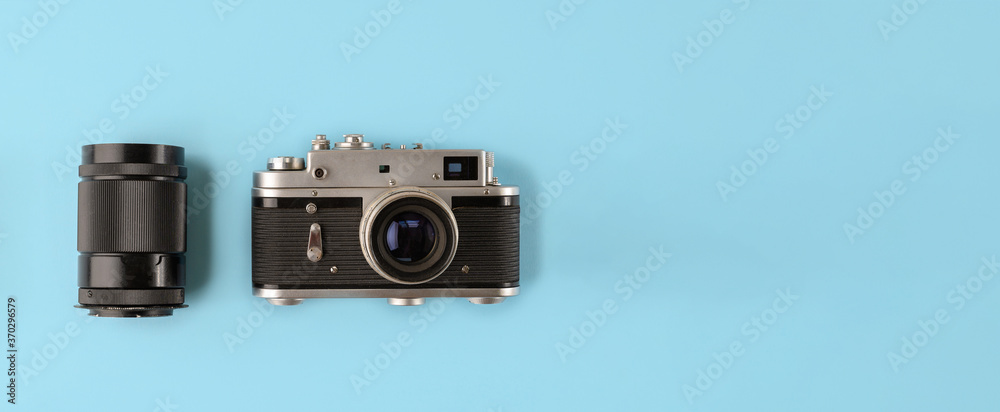 Fototapeta premium Retro photo camera with lens on blue background, top view