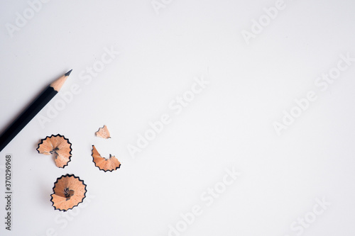 The cropped shot view of sharpened pencils of various lengths with a sharpener and pencil shavings on white background, blank copy space screen for your text message or information content.
