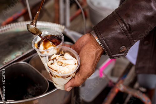Adding extra sugar syrup to 2 cups of Taho. Taho is a Philippine snack made of soft tofu, carmelized sugar and sago pearls. photo